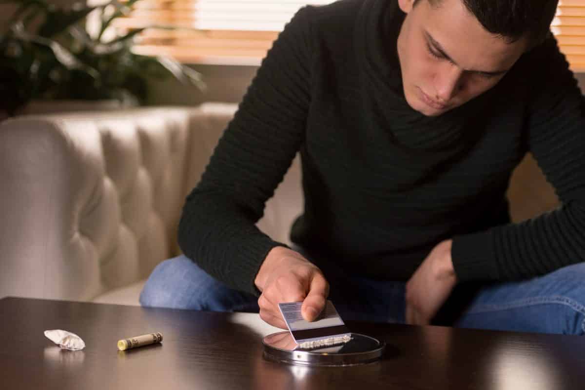 man setting up line of cocaine
