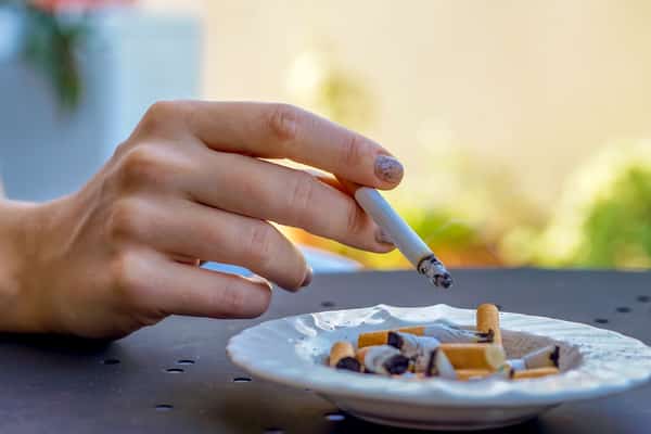 person tapping cigarette on ash tray