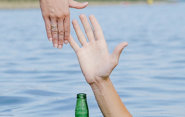 Hand reaching up of the water to hold another hand