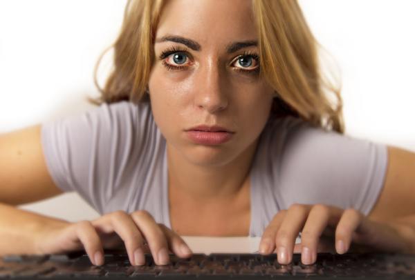 Young woman typing on a computer keyboard looking overwhelmed