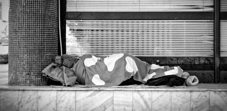Person lying on the ground with a blanket.