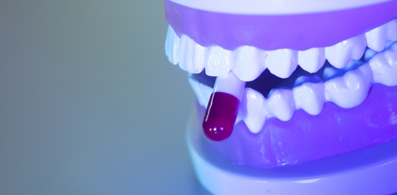 model of jaw with pill between teeth