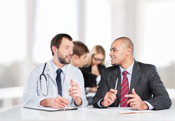 Medical doctor speaking with a man in a business suit.