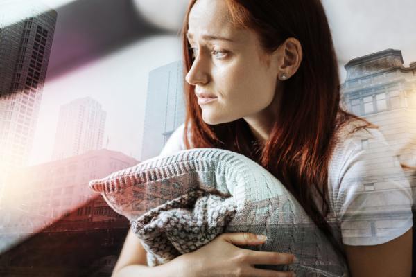 Woman holding a pillow looking sad.