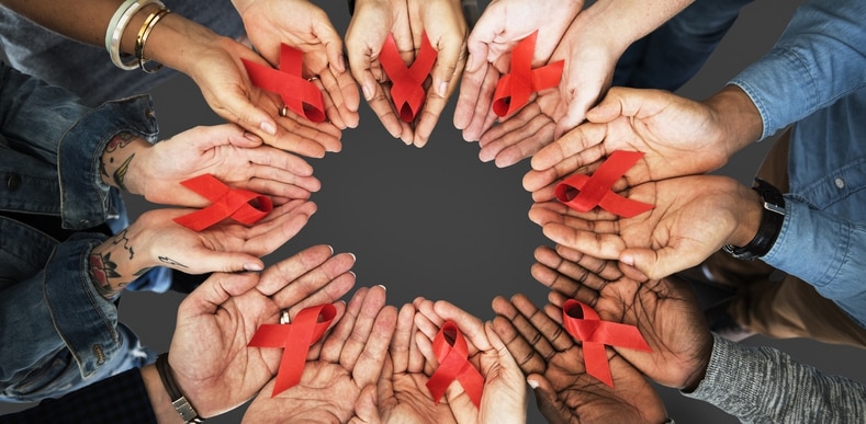 circle of hands holding red ribbons