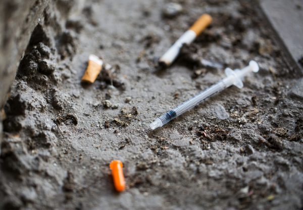 A cigarette and syringe on the ground. 