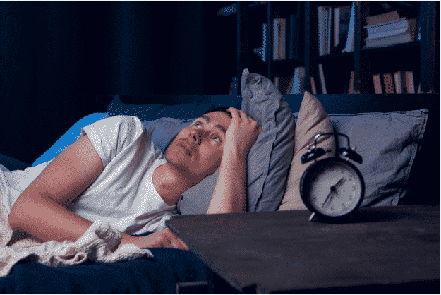 man with insomnia lying awake in bed