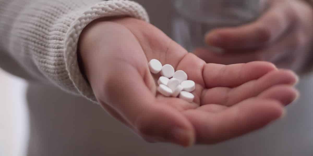 person holding Lortab tablets in hand