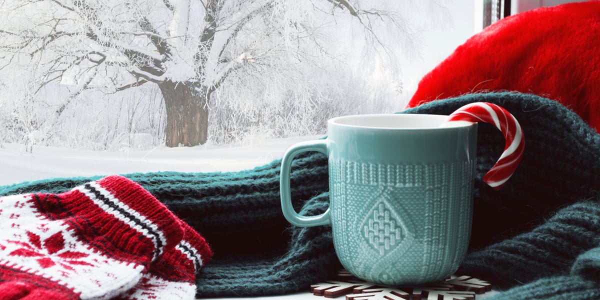 A cup of coffee next to winter clothes