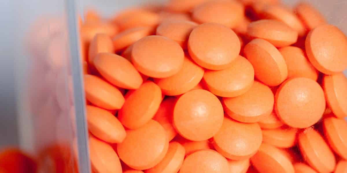 A pile of orange suboxone pills in a container