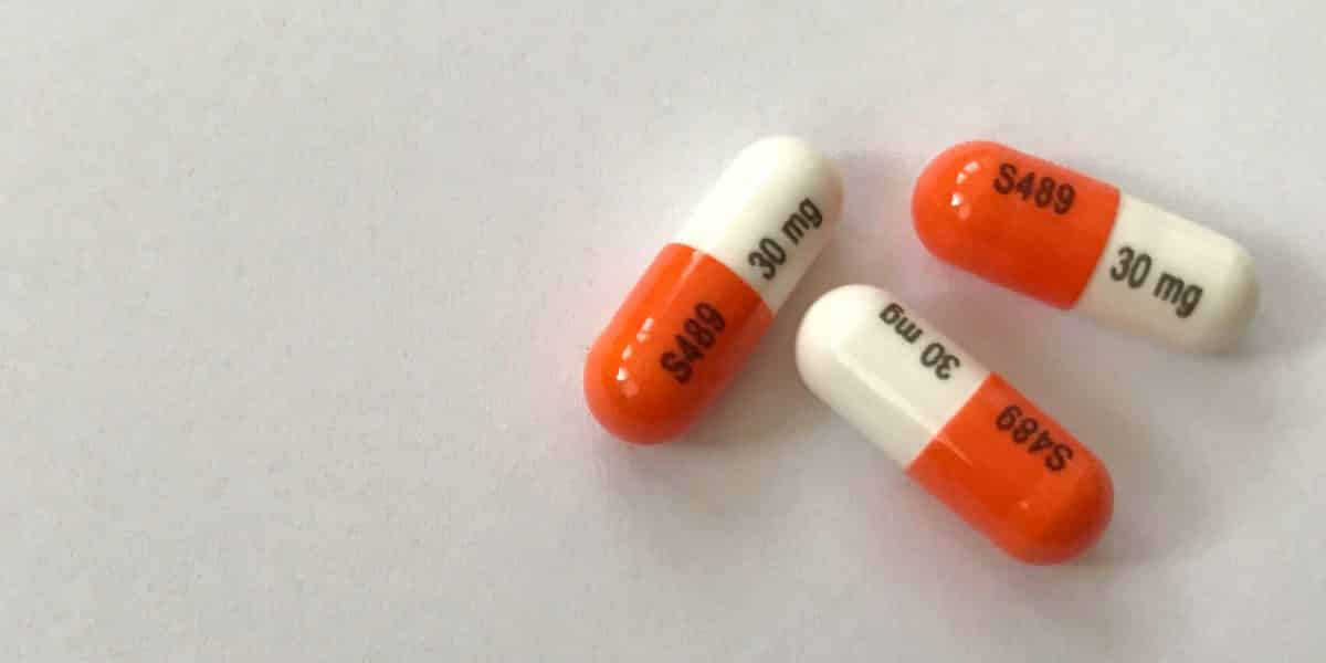 three orange and white Vyvanse pills sitting on a counter