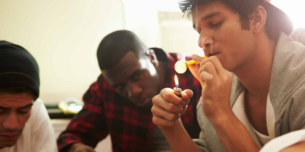 A group of guys smoking meth out of a glass pipe
