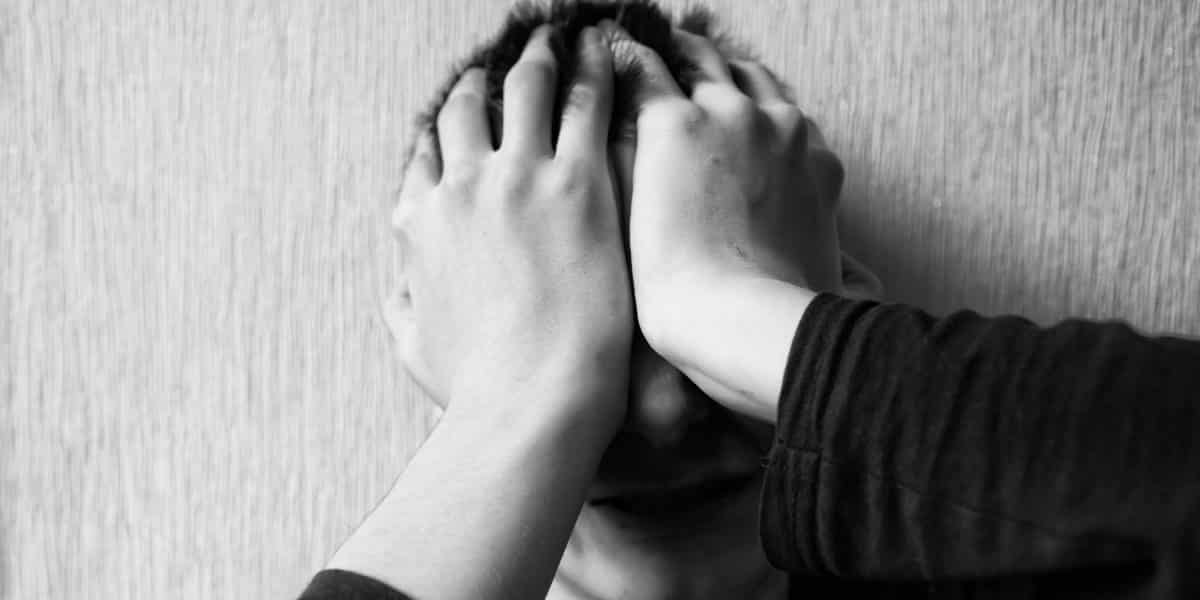 A distressed teen covering his face with his hands after overdosing on k2 spice