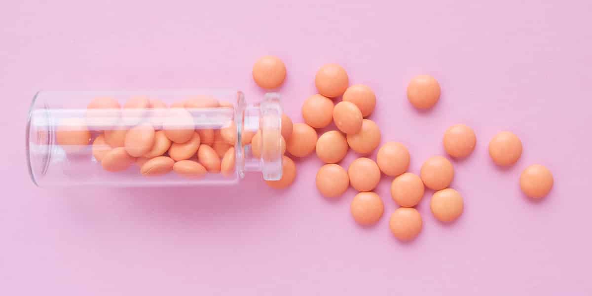 Pink suboxone pills spilling out of a glass prescription bottle