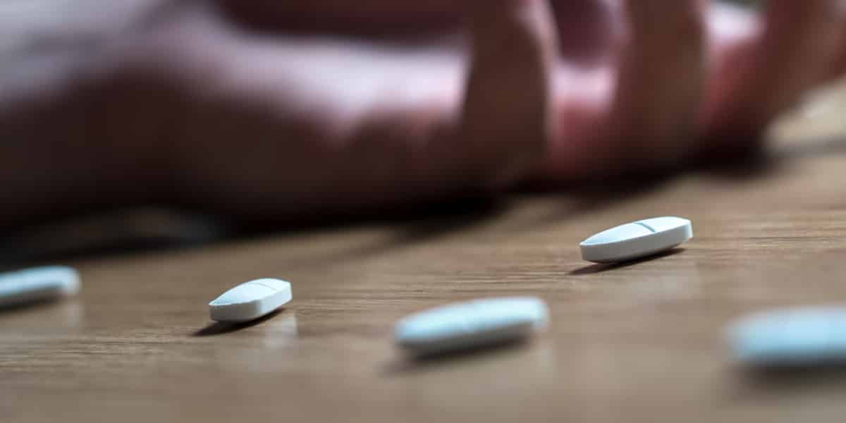 Xanax pills on the ground laying next to the hand of a person who overdosed