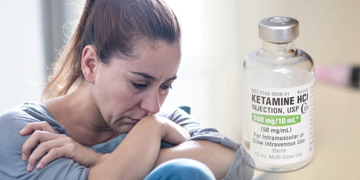 A distressed woman laying down in her bed experiencing ketamine withdrawal