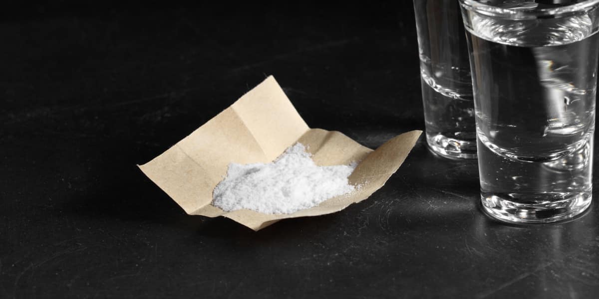 White meth powder next to two shot glasses filled with alcohol