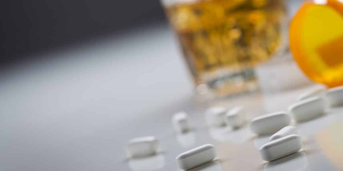 spilled tramadol pills next to alcoholic drink