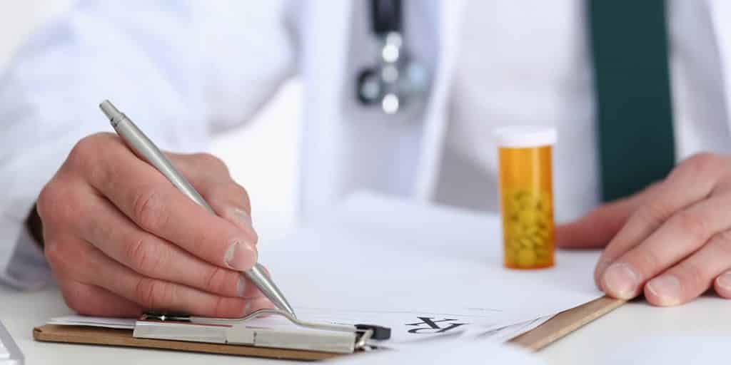 Doctor writing a patients a prescription for an opioid