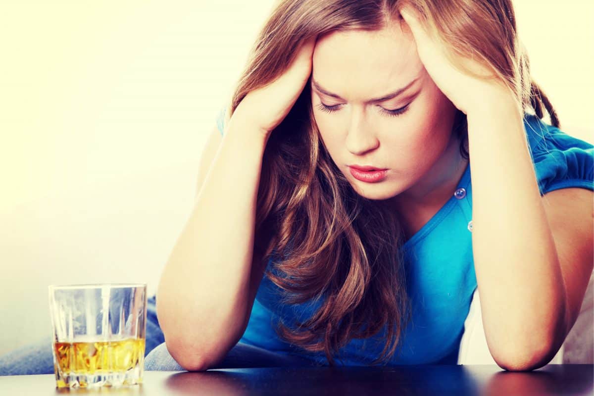 woman with anxiety sitting at a table with a drink